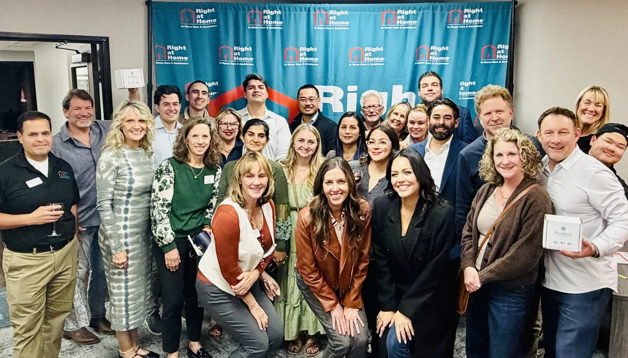 Group photo of diverse employees gathered in front of a Right at Home company backdrop.